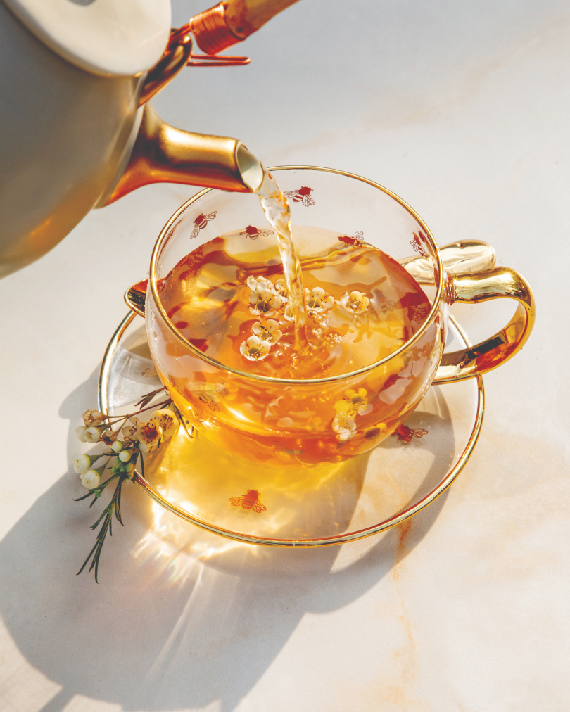 Tea being poured into a clear tea cup with gold accents